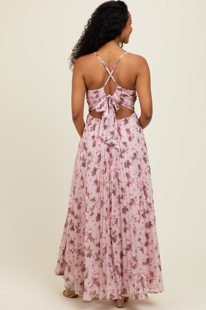 woman wearing a backless pink floral maxi dress with a tie detail and spaghetti straps
