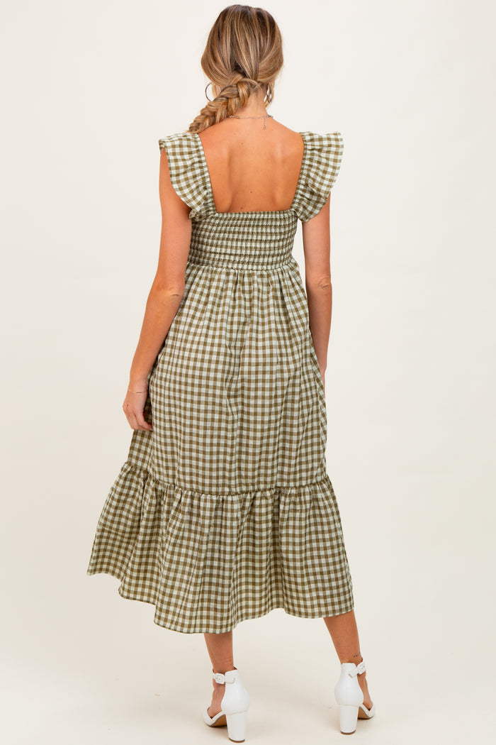 woman wearing a green and white gingham maternity dress with ruffled sleeves and a tiered hem, showing a bare back
