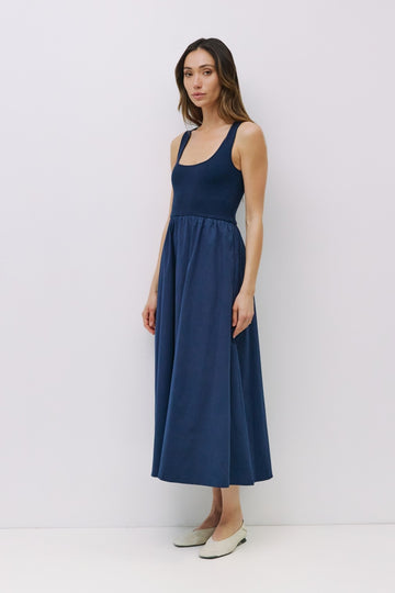 woman wearing a dark blue sleeveless maxi dress with a fitted bodice and flared skirt