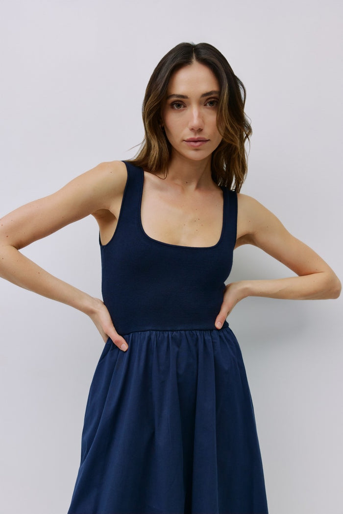 woman wearing a navy blue sleeveless dress with a fitted bodice and a flared skirt