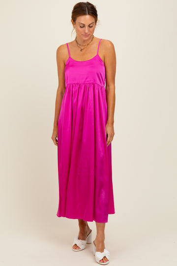 woman wearing a bright pink sleeveless maxi dress with a gathered waist and thin straps