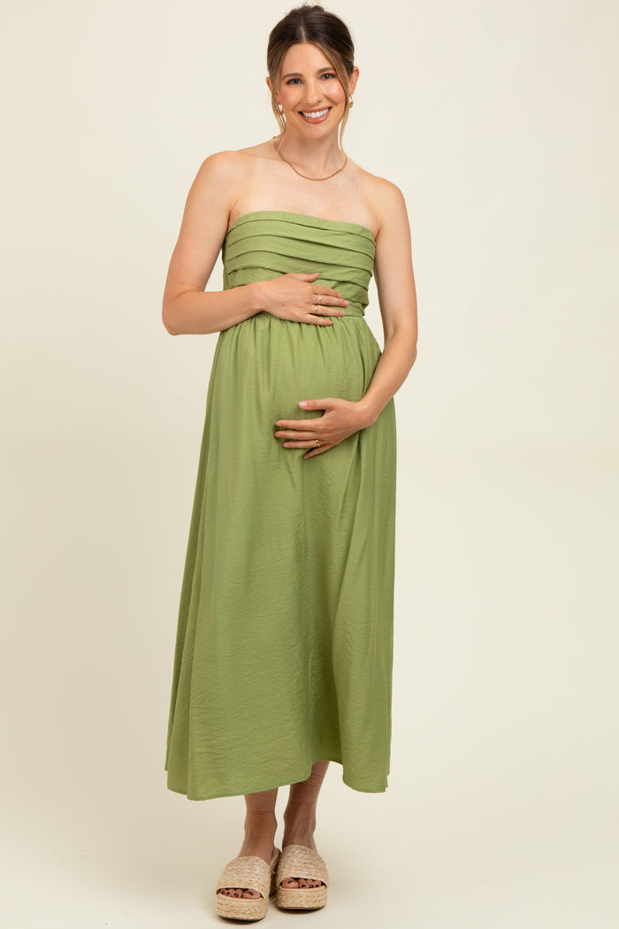 woman wearing a light green strapless maternity maxi dress and holding her baby bump