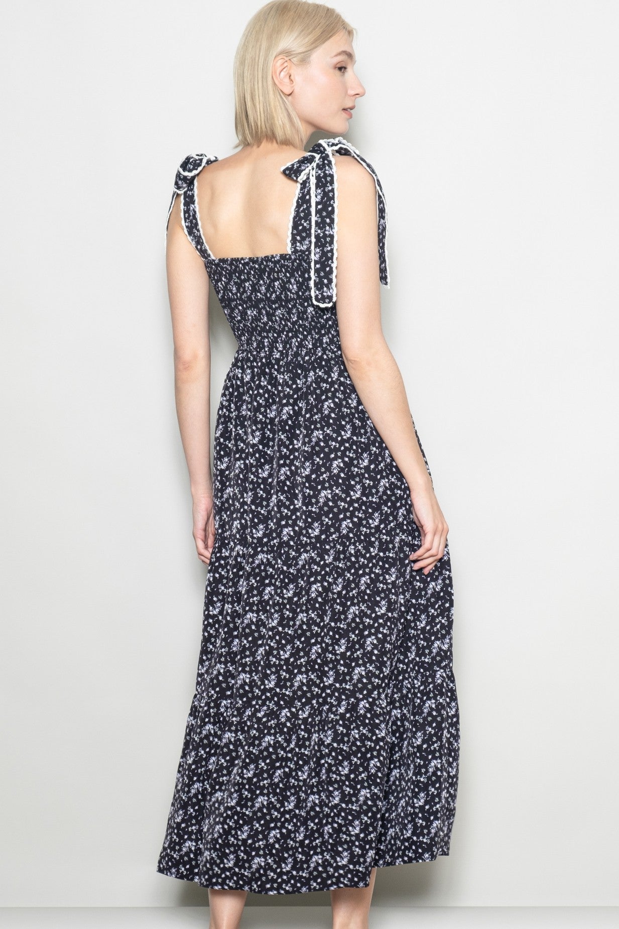 woman wearing a navy blue floral maxi dress with tie shoulder straps, showing the back view