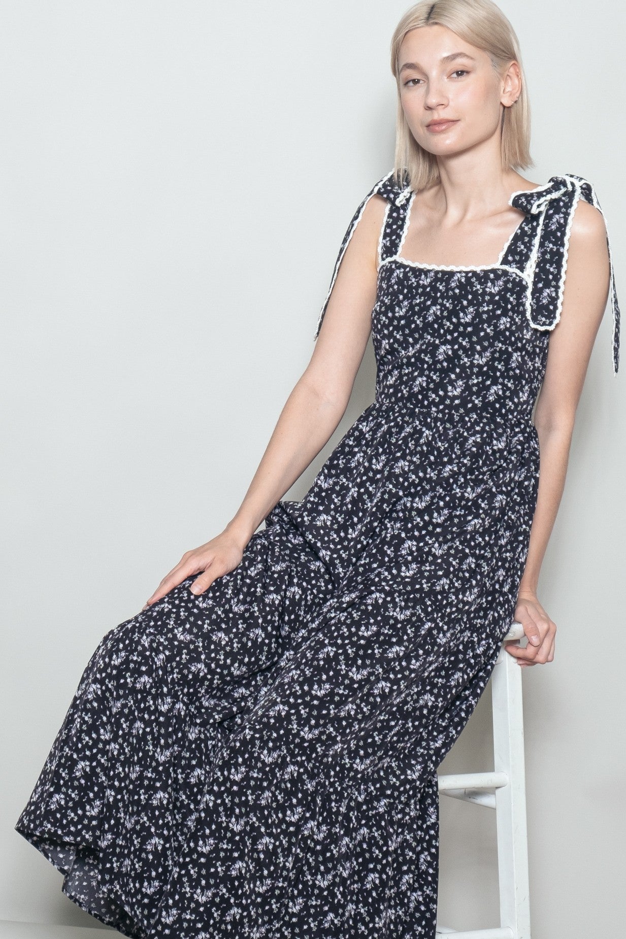 woman wearing a navy floral maxi dress with square neckline and tie shoulder straps