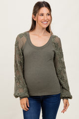 woman wearing a green maternity top with embroidered long sleeves and a rounded neckline, showcasing her baby bump