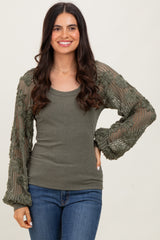 woman wearing an olive green ribbed top with lace sleeves and a relaxed fit, smiling against a neutral background