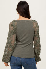 woman wearing an olive green ribbed top with floral mesh long sleeves and fitted style, seen from the back