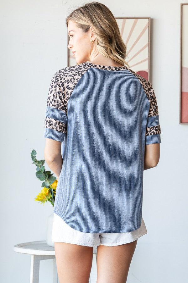 woman wearing a blue and leopard print short sleeve top, back view with a relaxed fit and ribbed texture