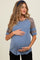 woman wearing a blue ribbed maternity top with leopard print sleeves and holding her baby bump