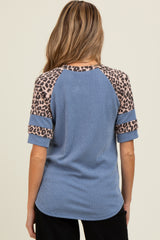 woman wearing a blue ribbed maternity top with leopard print sleeves, showing a relaxed fit from the back