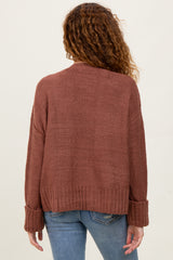 woman wearing a rust-colored oversized knit sweater with ribbed cuffs and a relaxed fit, shown from the back