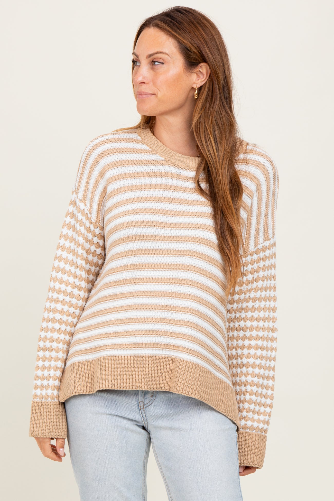 woman wearing a beige and white striped sweater with patterned sleeves and a relaxed fit