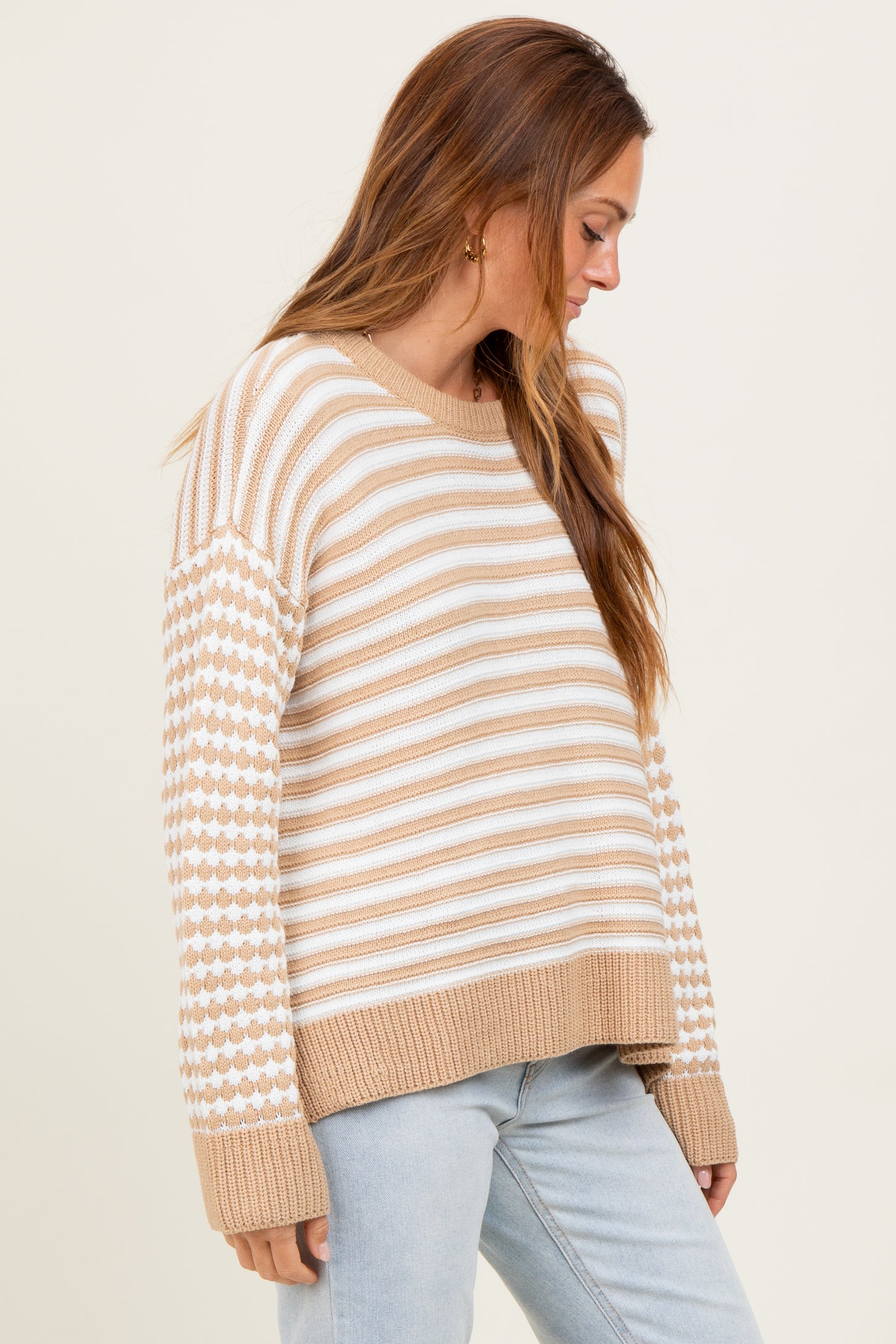 woman wearing a beige and white striped sweater with patterned sleeves and a ribbed hem