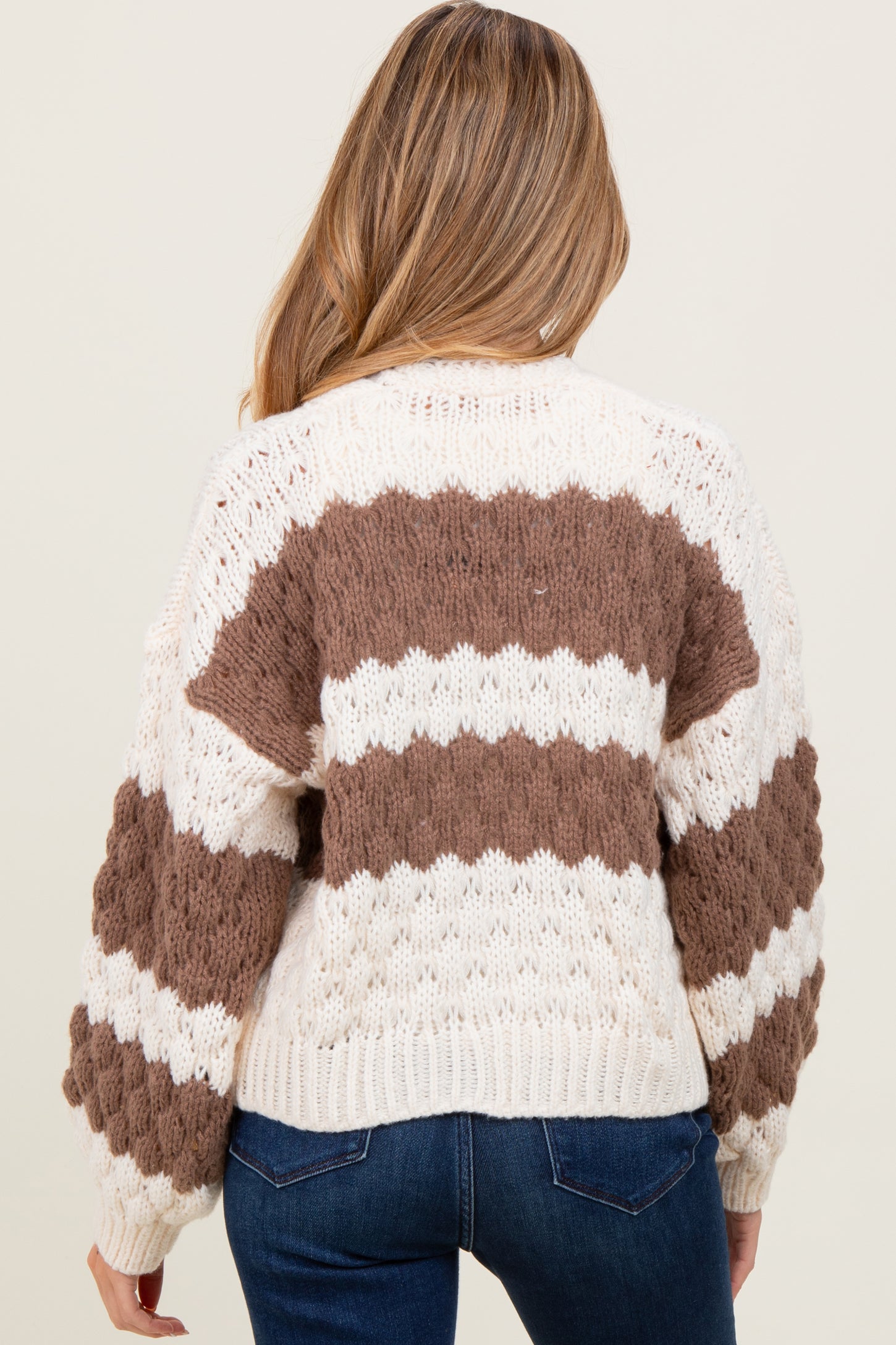 woman wearing a cream and brown striped oversized maternity sweater, with a loose fit and balloon sleeves