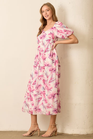 woman wearing a floral pink midi dress with puff sleeves and a fitted bodice