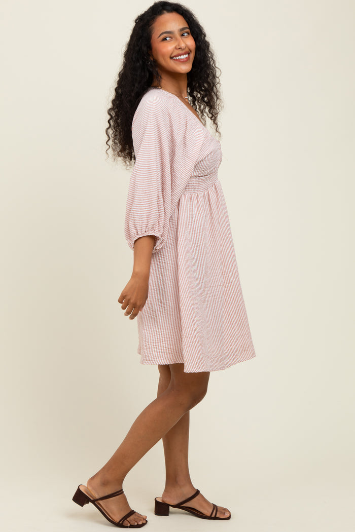 woman wearing a striped short sleeve dress with a fitted bodice and a flared skirt, smiling and standing sideways