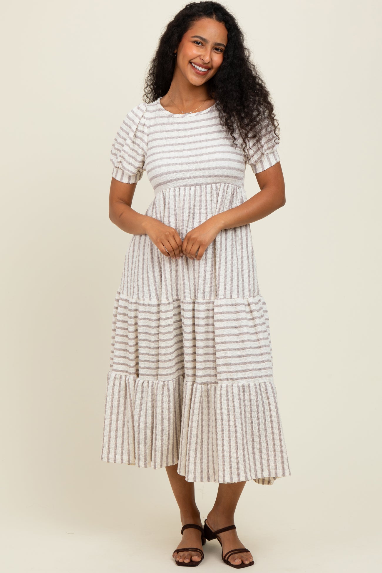 woman wearing a cream and brown striped midi dress with short sleeves and tiered ruffles