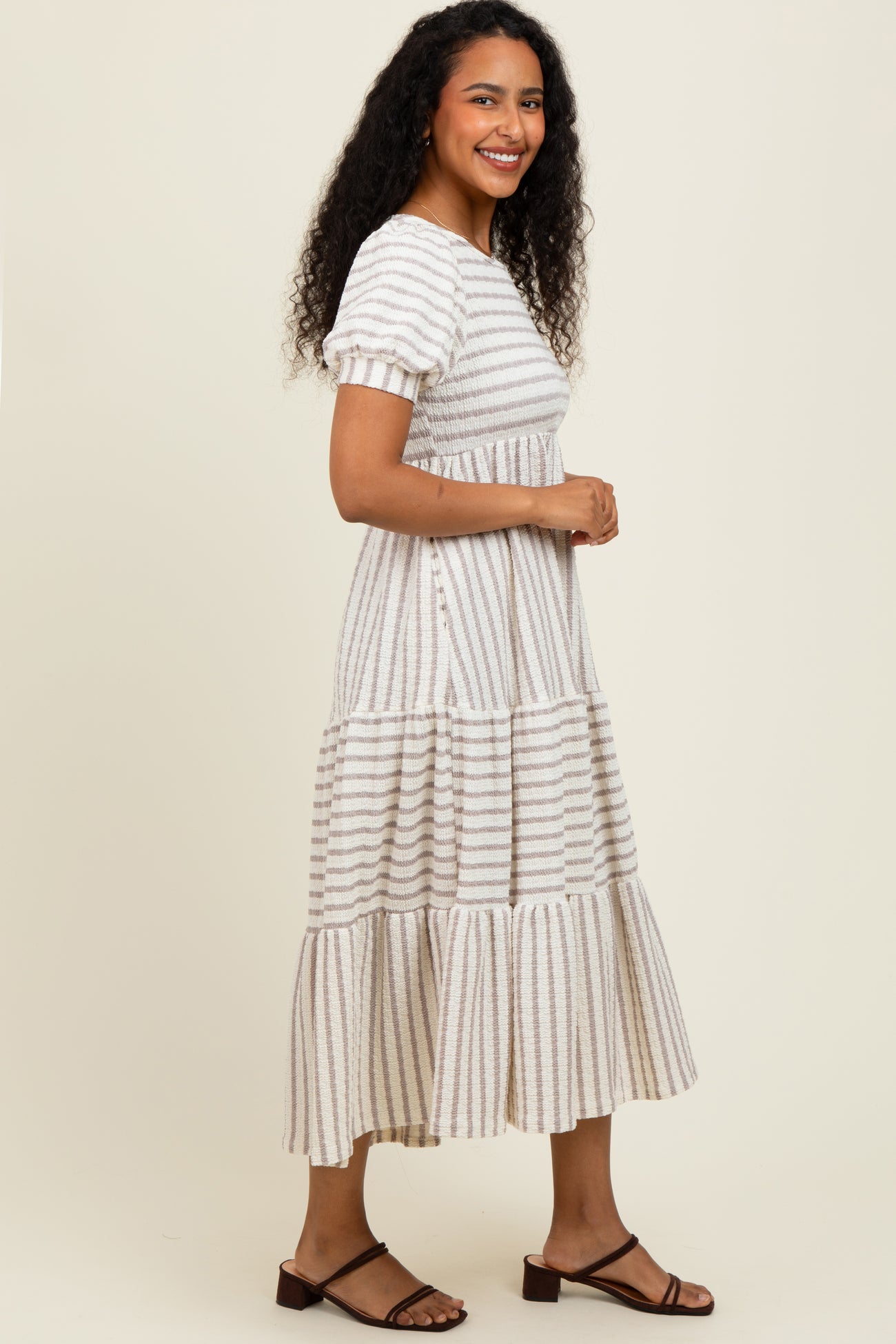woman wearing a beige striped tiered maxi dress with short sleeves and a relaxed fit
