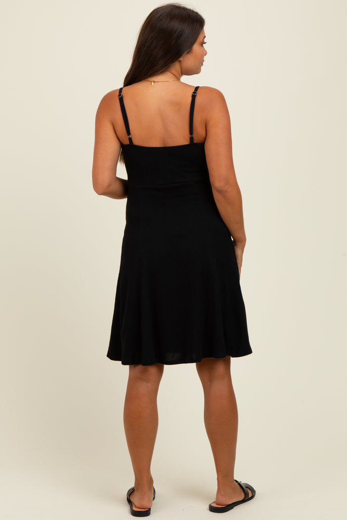 woman wearing a black spaghetti strap maternity dress, showing a flared skirt and styled for comfort during pregnancy