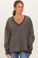 woman wearing a dark gray oversized v-neck sweatshirt with raw hem and long sleeves