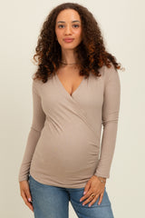 woman wearing a beige long sleeve maternity top with a wrap design and visible baby bump