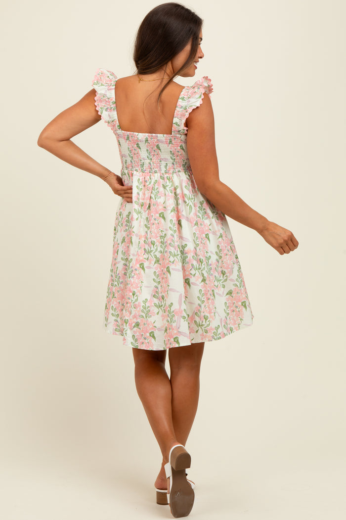 woman wearing a floral print maternity dress with ruffled sleeves and a smocked back, showing a baby bump
