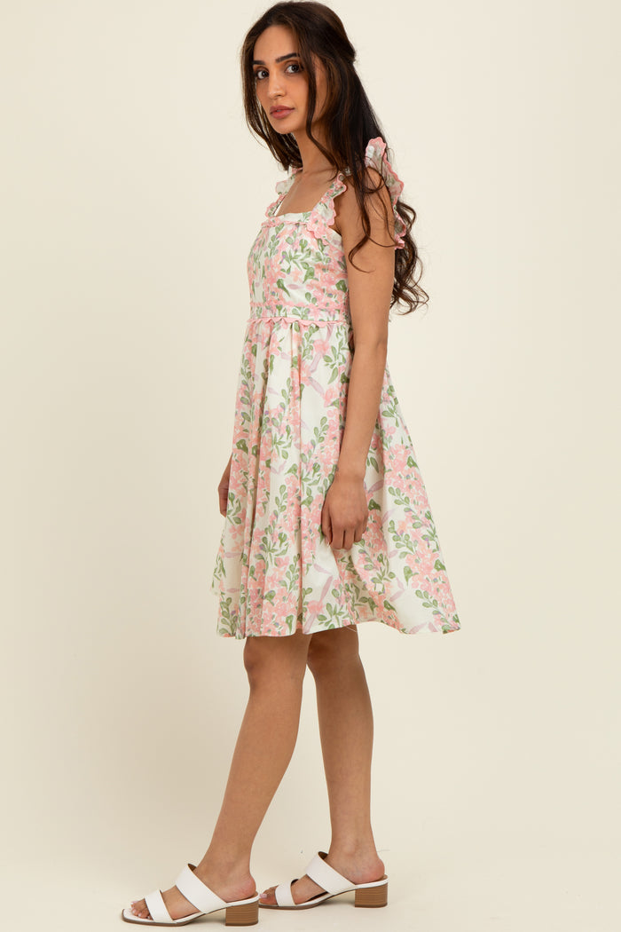 woman wearing a floral pattern midi dress with shoulder bows and a flared skirt, paired with white sandals