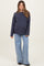 woman wearing a navy blue cable knit maternity sweater and light blue wide-leg jeans, with a visible baby bump