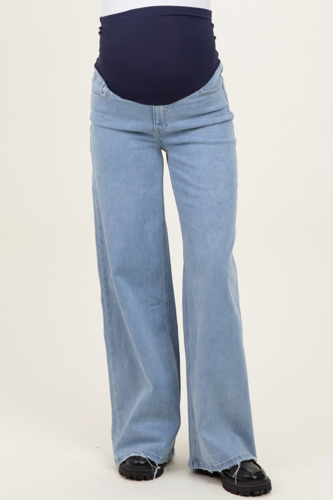 woman wearing light wash maternity wide-leg jeans with a navy blue belly band, styled with black shoes