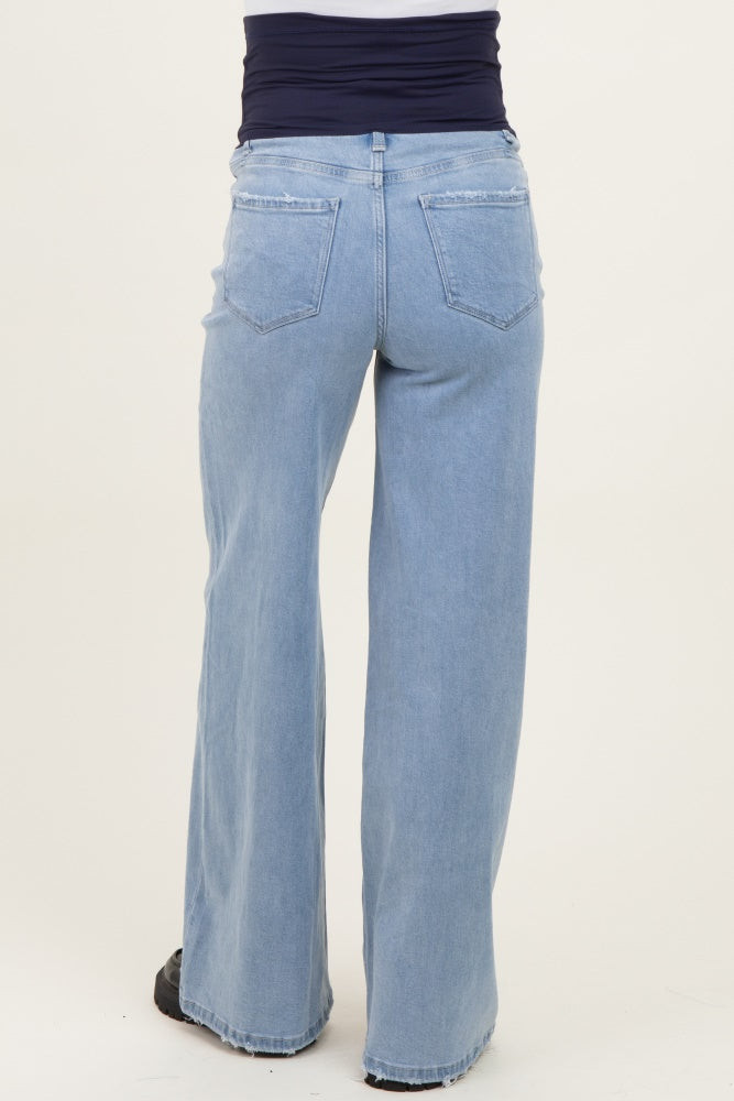 woman wearing light blue maternity jeans, viewed from the back, featuring a wide-leg style and an elastic waistband