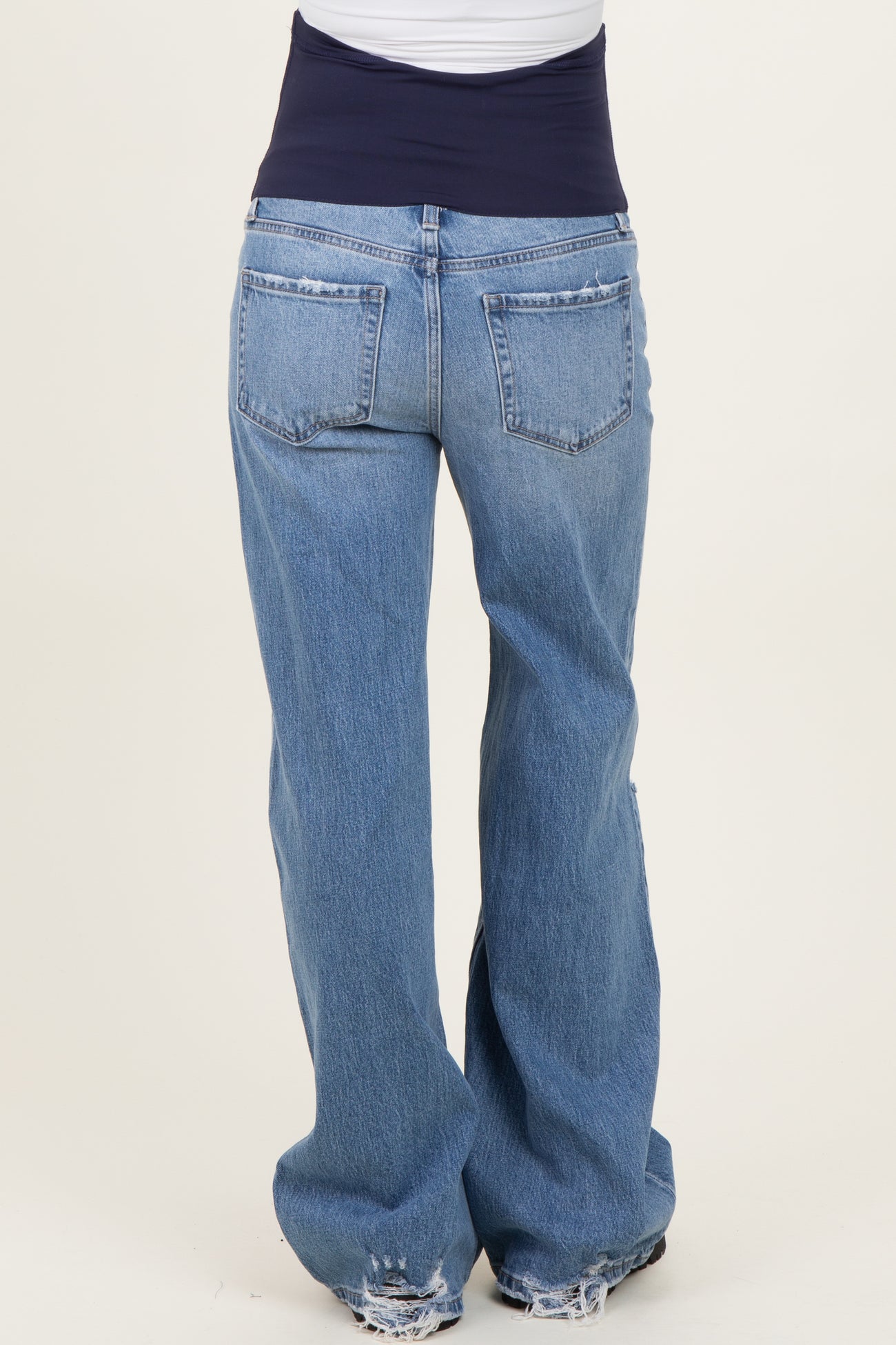 woman wearing distressed blue maternity jeans with a navy waistband, viewed from the back