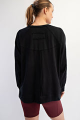 woman wearing a black oversized sweatshirt with a yoke detail and long sleeves, showing the back view