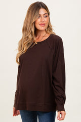 woman wearing a brown long sleeve maternity top with a relaxed fit and visible baby bump