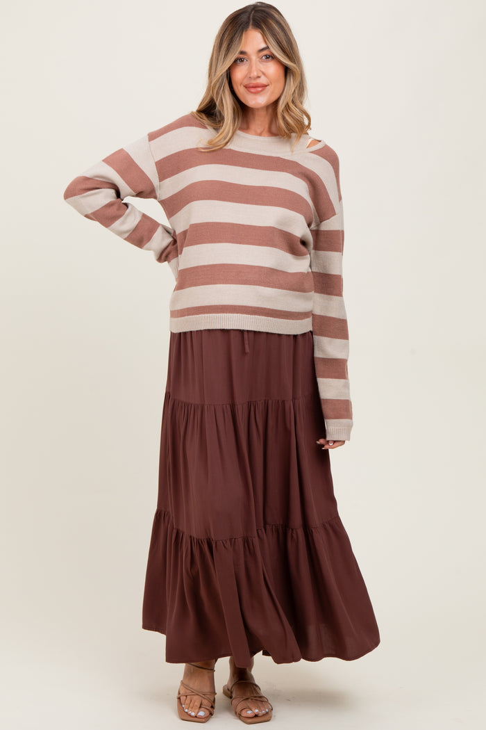 woman wearing a striped brown and beige maternity sweater with a brown tiered maxi skirt and a visible baby bump
