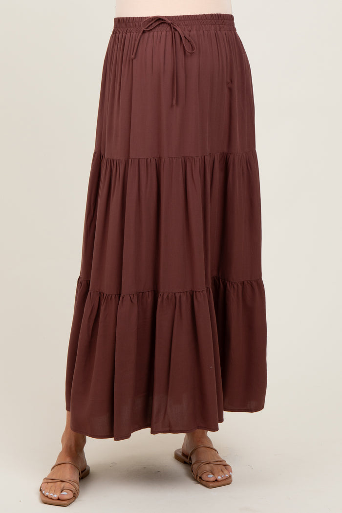 woman wearing a brown tiered maternity maxi skirt with an elastic waistband and drawstring detail