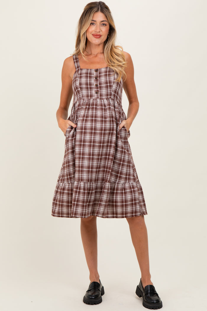 woman wearing a brown and white plaid maternity dress with pockets and a tiered skirt
