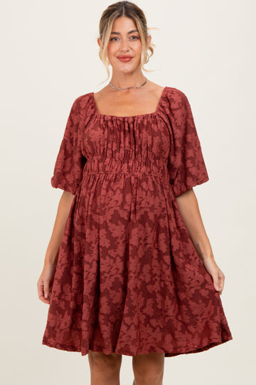 woman wearing a rust colored floral print maternity dress with square neckline and puff sleeves