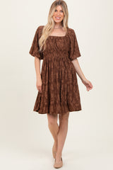 woman wearing a brown floral print short dress with a square neckline and short sleeves