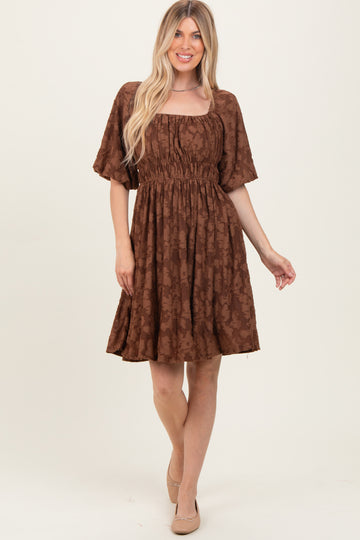 woman wearing a brown floral print short dress with a square neckline and short sleeves