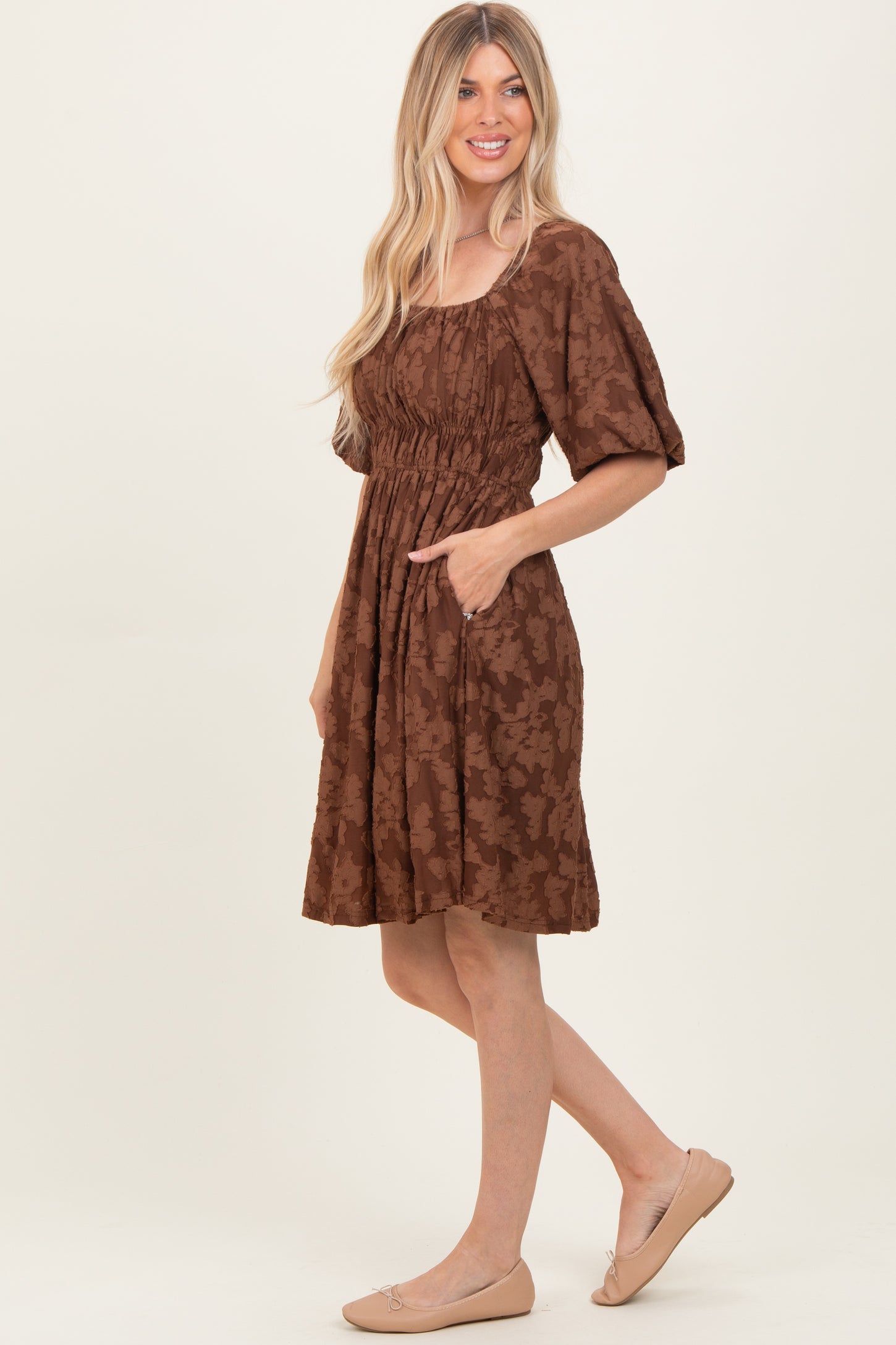 woman wearing a brown floral print short sleeve dress with pockets and a cinched waist