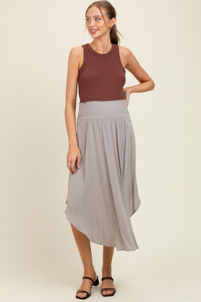 woman wearing a maroon tank top and a light gray maternity skirt with a smocked waistband