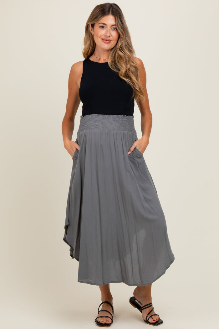 woman wearing a black sleeveless top and a flowy gray maternity skirt with side pockets