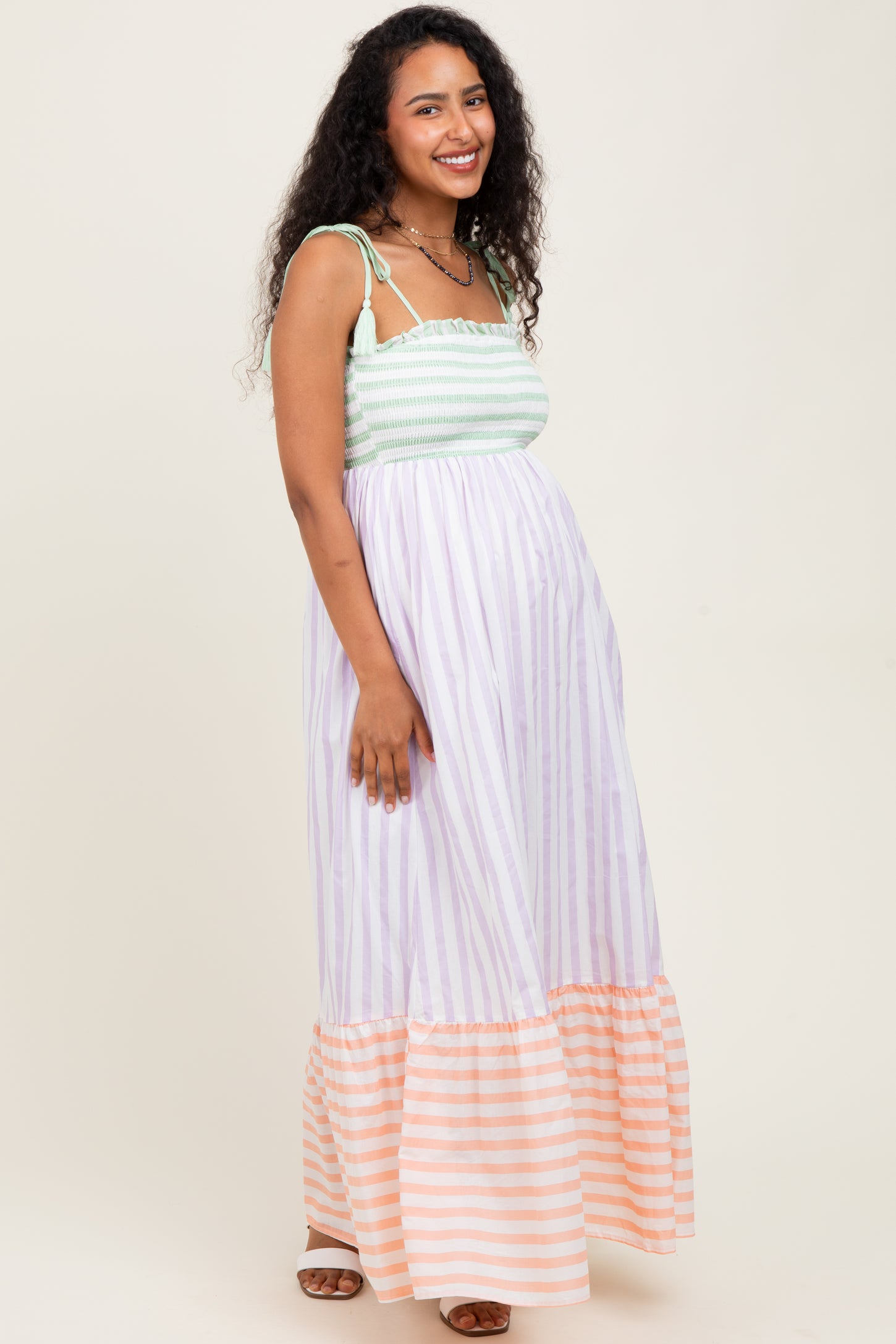 woman wearing a striped maternity maxi dress with a smocked bodice and a ruffled hem, showcasing her baby bump