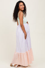 woman wearing a mint green maternity top with a lavender and coral striped maxi skirt, showing her baby bump