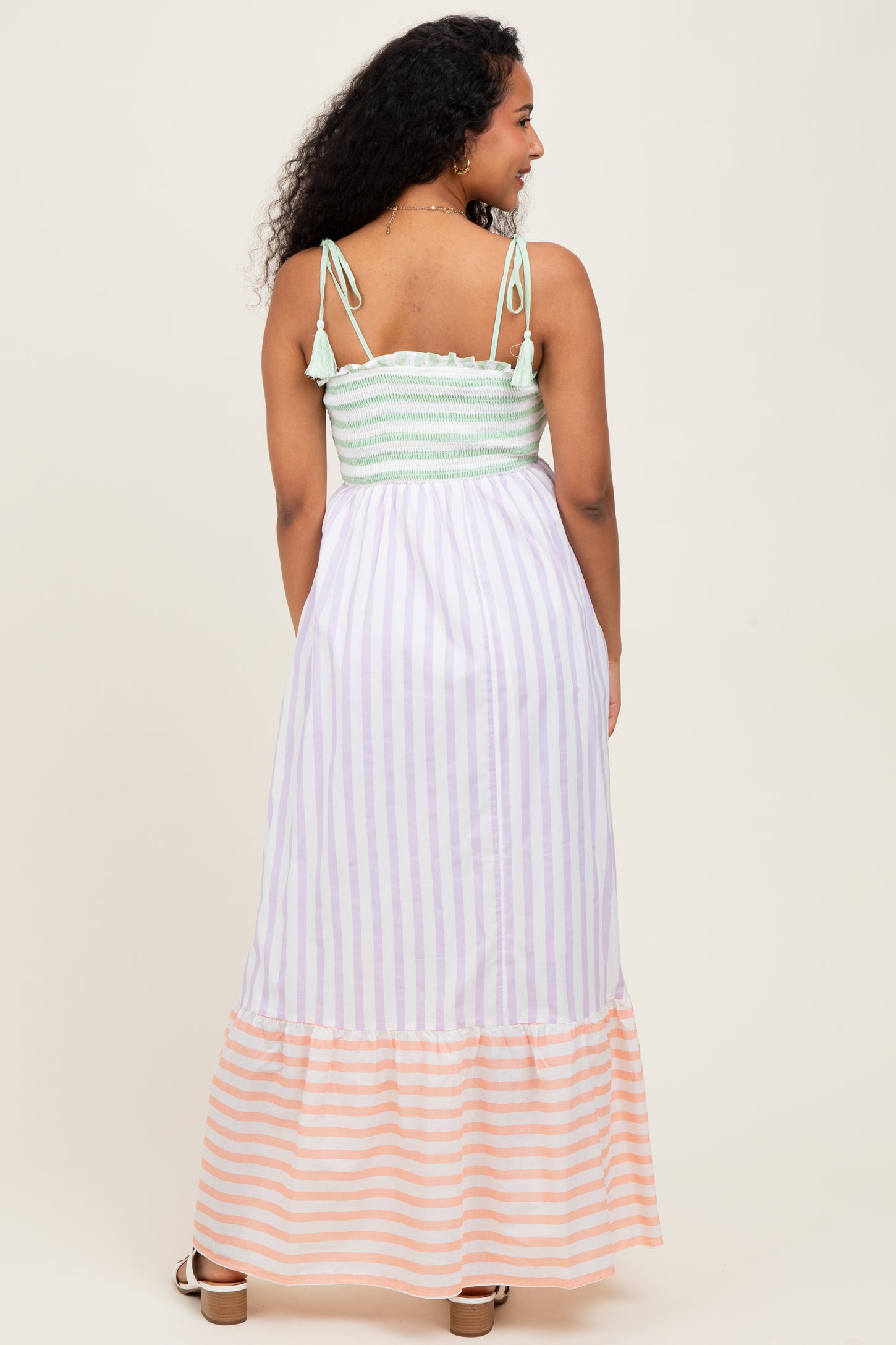 woman wearing a striped maternity maxi dress with a soft green smocked bodice and a flowy striped skirt