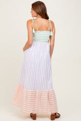 woman wearing a green and white striped smocked maxi dress with orange and white striped bottom hem