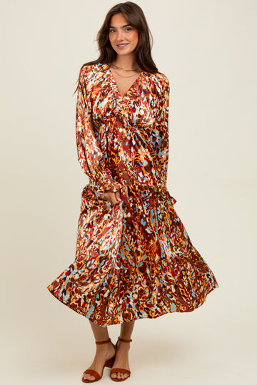 woman wearing a brown floral print long sleeve maxi dress with a ruffled hem and holding the skirt while posing