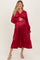 woman wearing a red satin maternity dress with long sleeves and tiered hem, showcasing her baby bump