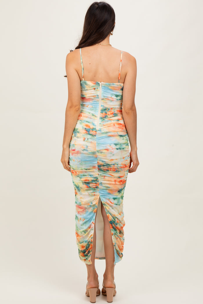 woman wearing a colorful tie-dye midi dress with a ruched design and a back slit