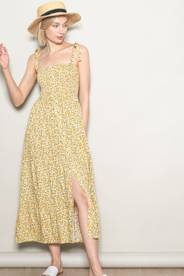woman wearing a yellow floral maxi dress with tie straps and a side slit